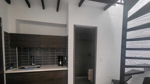 Una cocina moderna con armarios oscuros, salpicadero de azulejos y una cafetera en la encimera.