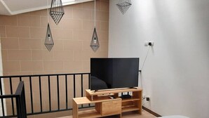 Un dormitorio moderno con una cama, un televisor sobre un soporte de madera y lámparas colgantes.