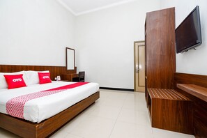 A hotel room with a wooden bed, red and white bedding, a flat-screen TV, and a wooden bench.