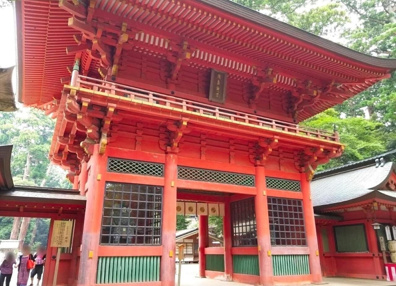 A traditional Japanese building with a red and green color scheme, featuring a prominent entrance with a tiled roof and a wooden lattice design.