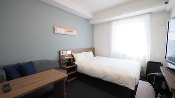 Habitación de hotel con cama, sofá, escritorio y cafetera.