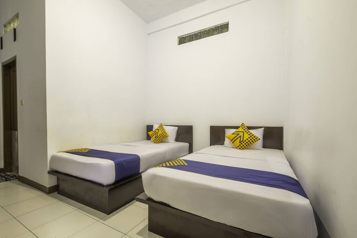 Een hotelkamer met twee bedden, elk voorzien van een blauw-witte dekbedovertrek en een geel kussen.
