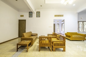 Un salón amplio con un sofá beige, muebles de madera y un sillón amarillo.
