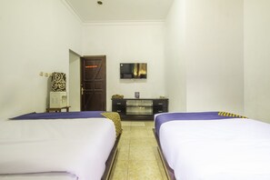Une chambre d’hôtel avec deux lits, un minibar, une télévision à écran plat et une porte donnant sur une autre chambre.