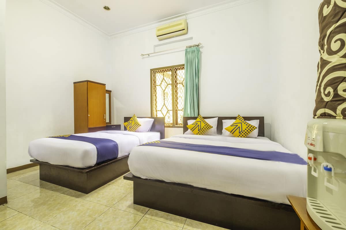 Een hotelkamer met twee bedden, een kledingkast, een raam met gordijn en een airconditioning.