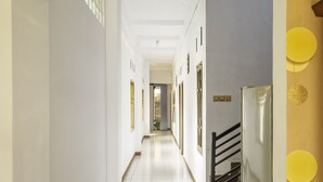 A hallway with white walls, a tiled floor, and a staircase with a metal railing. - SPOT ON 2395 Hotel Aden 2 Syariah (Tasikmalaya)