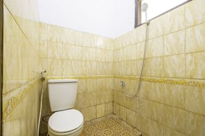 Une petite salle de bain avec des carreaux jaunâtres à motifs, des toilettes et une douche.