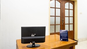 A reception desk with a computer monitor and a sign indicating check-in times. - OYO 2268 Tim-tim Homestay SyariahNearUniversitas Gadjah Mada (Depok)