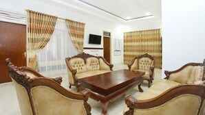 A room with a large wooden table, four upholstered chairs, and a television on the wall. - OYO 2268 Tim-tim Homestay SyariahNearUniversitas Gadjah Mada (Depok)