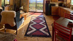 Eine gemütliche Küche mit Steinwand, Holzschränken und einem großen Fenster mit Blick auf die Berge.