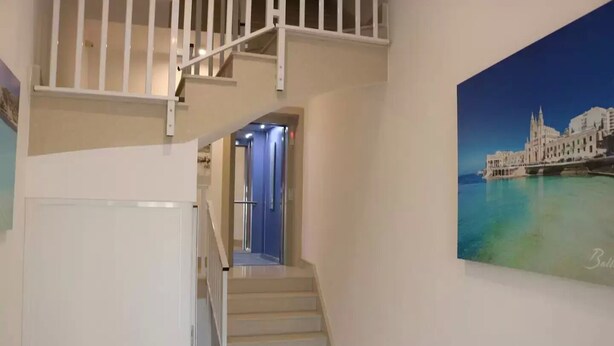 Eine Treppe führt zu einer zweiten Etage mit Blick auf eine Küstenstadt.