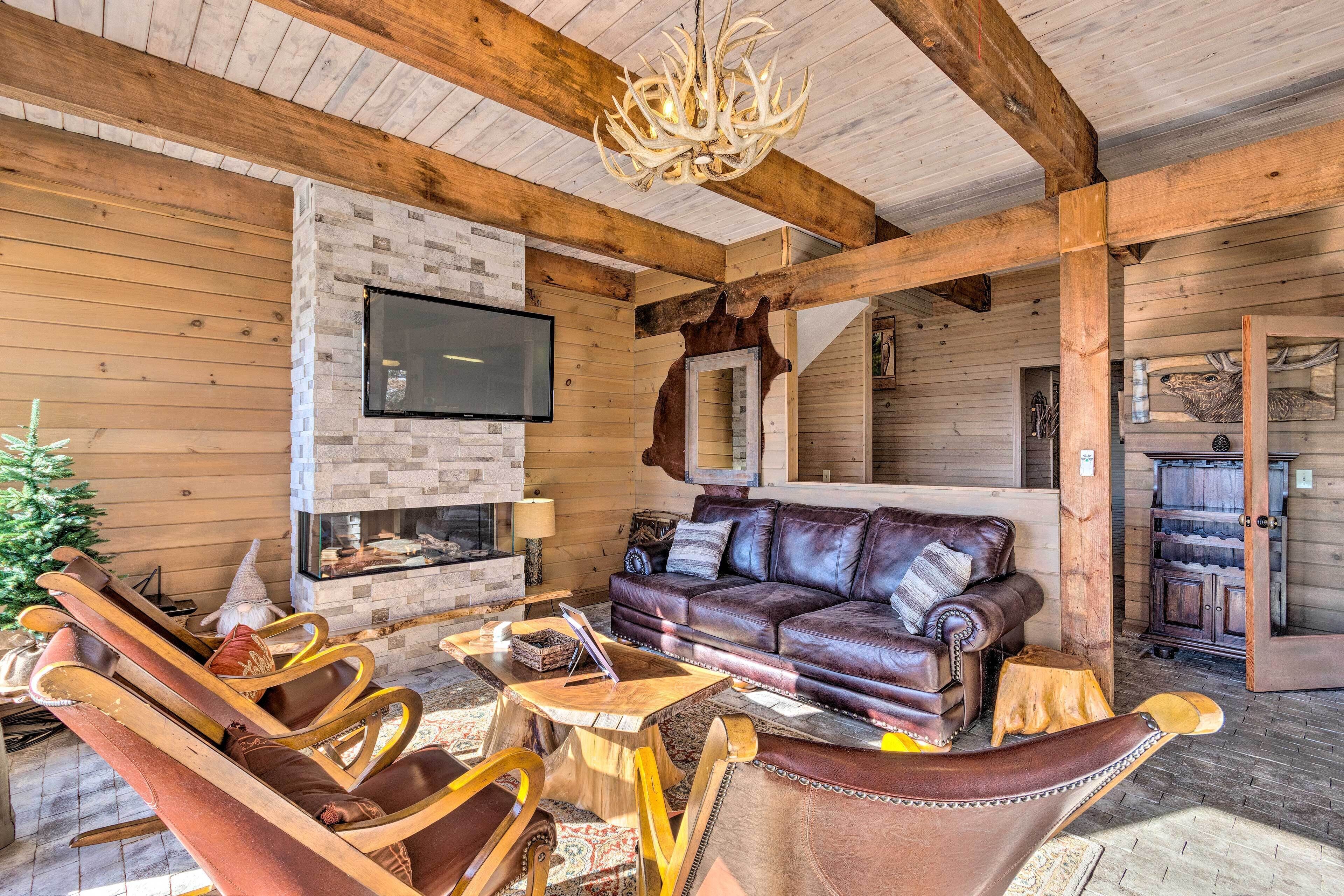 A cozy log cabin interior with a leather sofa, wooden rocking chairs, and a fireplace.