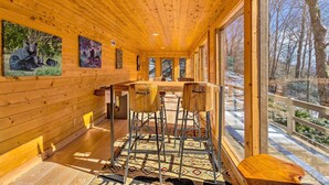 A wooden interior with a bar area, large windows, and artwork on the walls. - Golf, Sauna, Creek: Spectacular Smoky Mtn-View Gem (Maggie Valley)