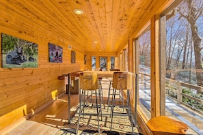 A wooden interior with a bar area, large windows, and artwork on the walls. - Golf, Sauna, Creek: Spectacular Smoky Mtn-View Gem (Maggie Valley)