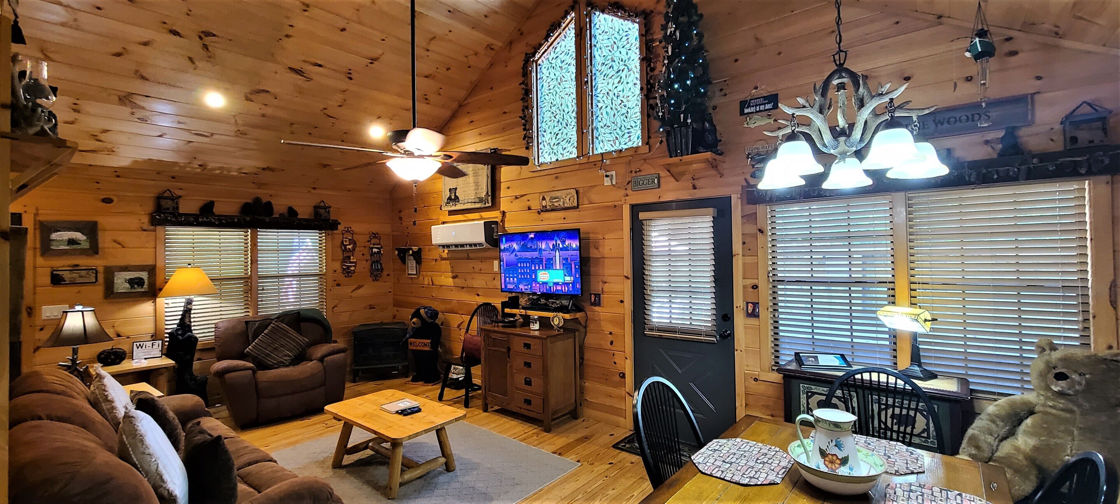Interior acogedor de una cabaña con detalles de madera, un televisor, chimenea y una estatua de un oso.