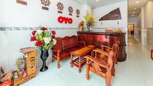 A lobby with wooden furniture, a reception desk, and wall decorations including ship wheels and a sign reading "OYO". - Hoa Giay Hotel (Nha Trang)