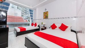 A hotel room with two beds, a large window with a view of buildings, a ceiling fan, and a painting on the wall. - Hoa Giay Hotel (Nha Trang)