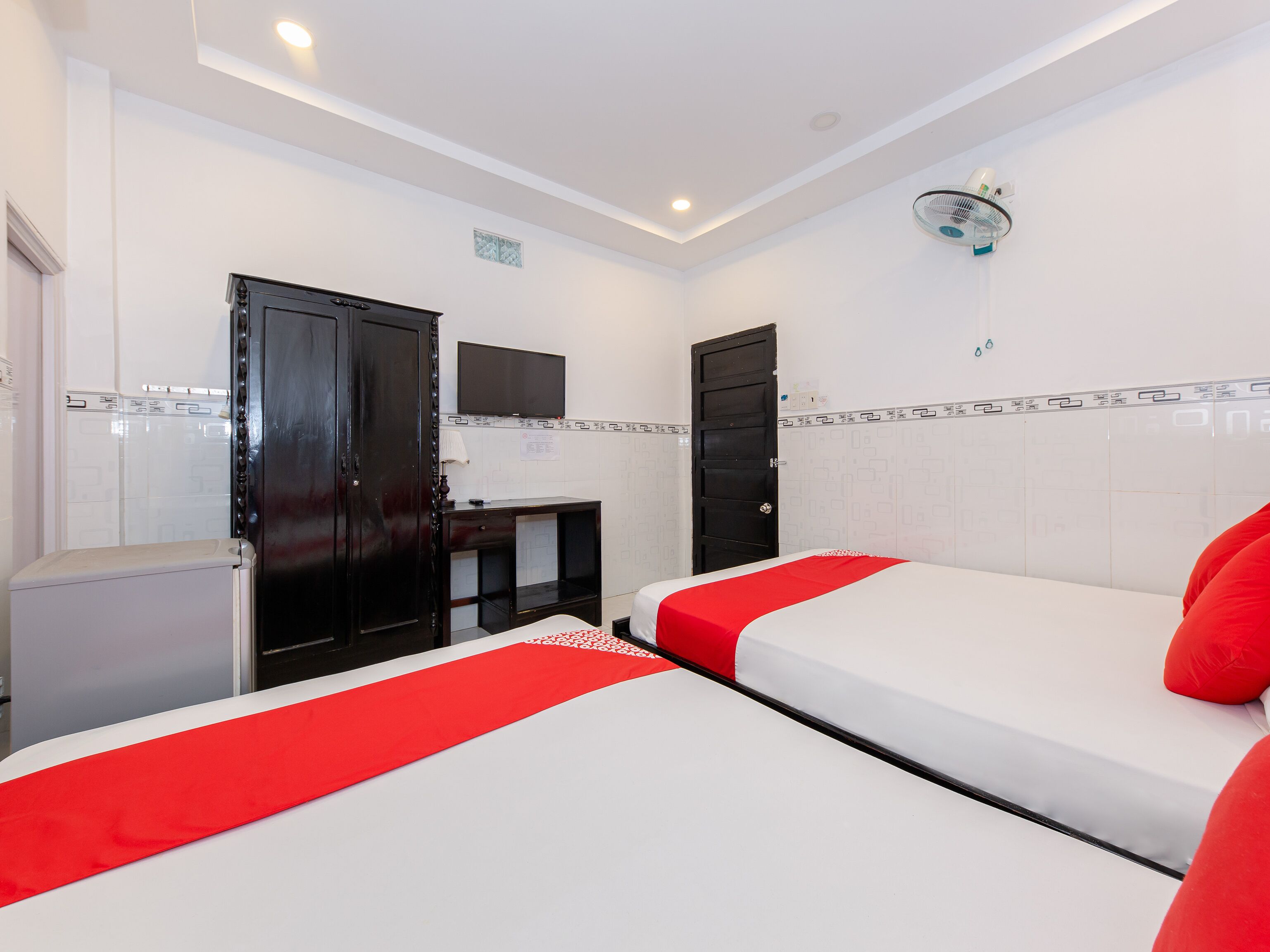 A hotel room with two beds, a desk, a TV, and a wardrobe.