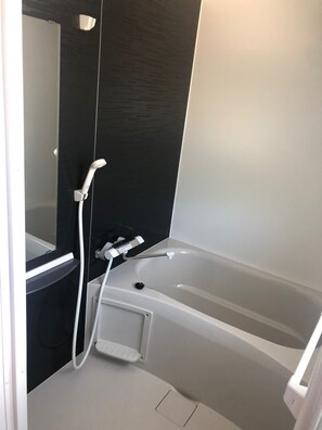 A modern bathroom with a bathtub, a shower, and a vanity with a mirror. - Churaumi Kafuu Terrace (Motobu)