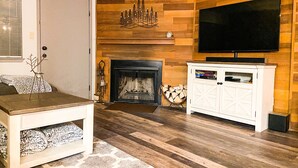 A living room with a fireplace, a television mounted on the wall, and a white cabinet. - Ski-In Ski-Out Brian Head Giant Steps Condo (Brian Head)