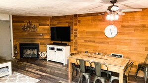 A dining area with a wooden table and chairs, a television mounted on the wall, and a fireplace. - Ski-In Ski-Out Brian Head Giant Steps Condo (Brian Head)