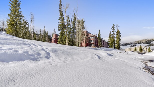 A snow-covered slope with a building featuring multiple balconies and a ski lift in the background. - Ski-In Ski-Out Brian Head Giant Steps Condo (Brian Head)