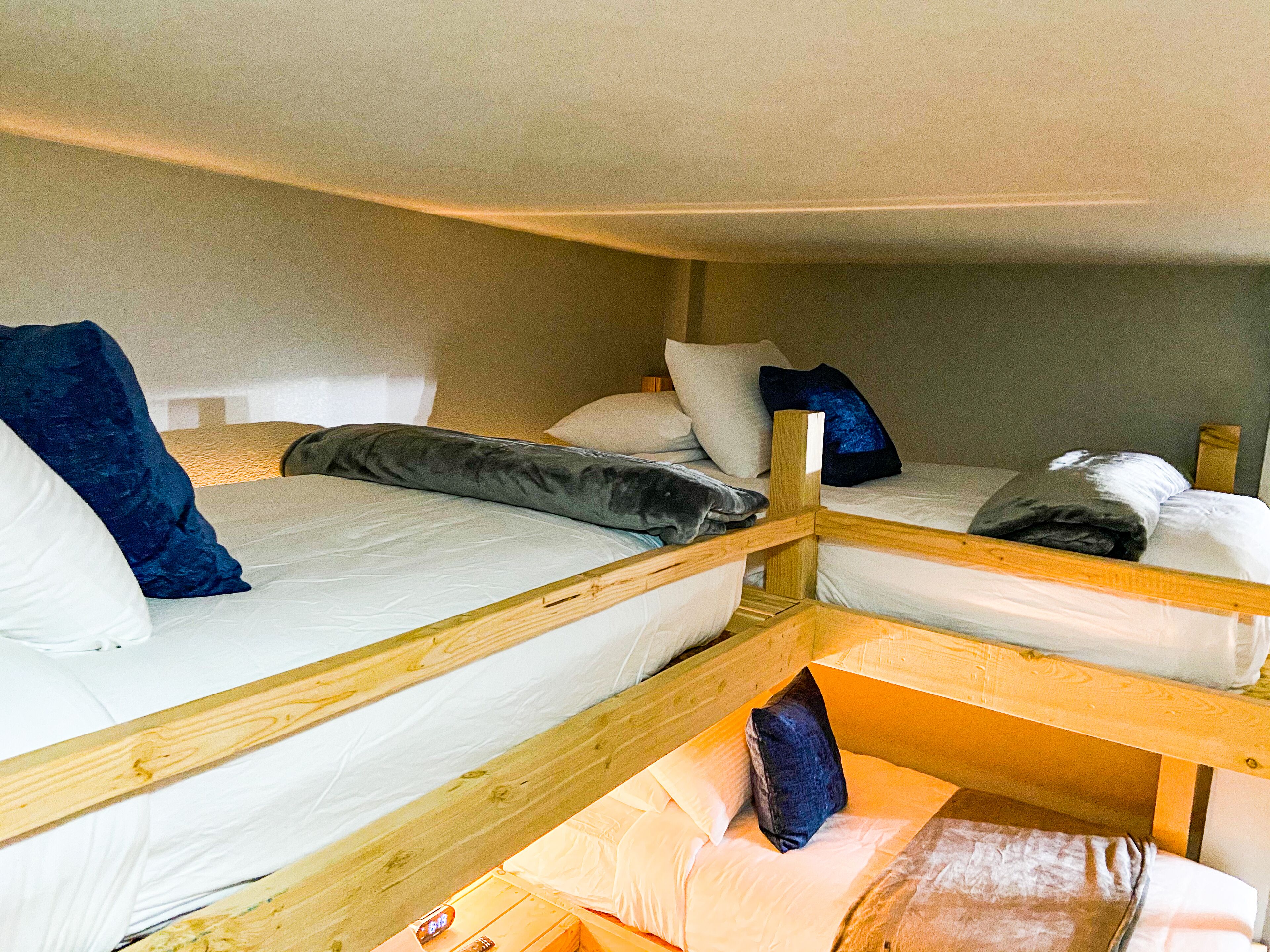 A bunk bed room with wooden railings, white bedding, and multiple pillows.