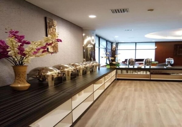 Una moderna zona de recepción de hotel con una larga barra de mostrador, un jarrón de flores y un amplio ventanal que proporciona luz natural.