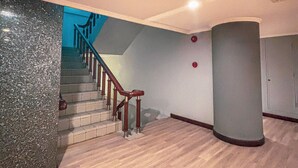 A spacious interior with a wooden staircase, a large pillar, and a view of the sky through a window. - Hotel Zia Sanno Jakarta - Pluit (Jakarta)