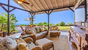 An outdoor covered patio with wicker furniture, a wooden bar, and a view of the ocean. - The “Promise Tree” is a great family  gathering place in Kailua Kona! (Kailua-Kona)