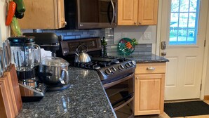 Cozinha com bancadas de granito, fogão, micro-ondas e armários de madeira.