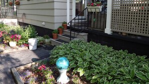Uma casa residencial com varanda da frente, degraus e vasos de plantas.