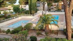 A residential area with a swimming pool, palm trees, and a gated entrance.