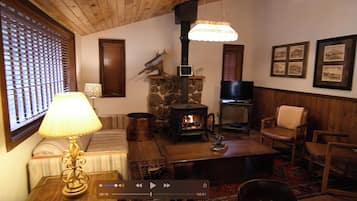 Un salon chaleureux avec une cheminée en pierre, un téléviseur et des meubles en bois.