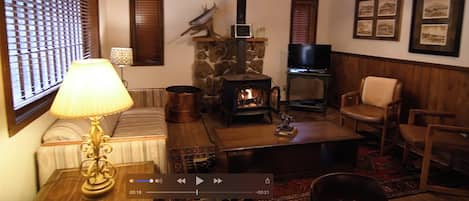 A cozy living room with a stone fireplace, a television, and wooden furniture.