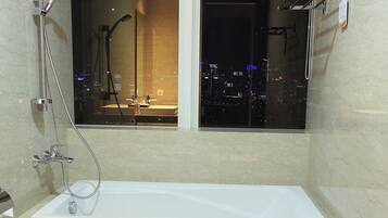 Een moderne badkamer met een bad, douche en toilet.
