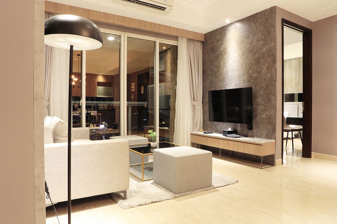 A modern living room with a sofa, ottoman, coffee table, and a flat-screen TV.