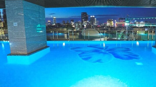 Una piscina en la azotea con vistas a un horizonte urbano nocturno.