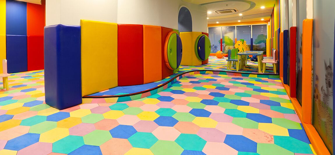 A play area with colorful padded walls and a multicolored hexagonal floor.