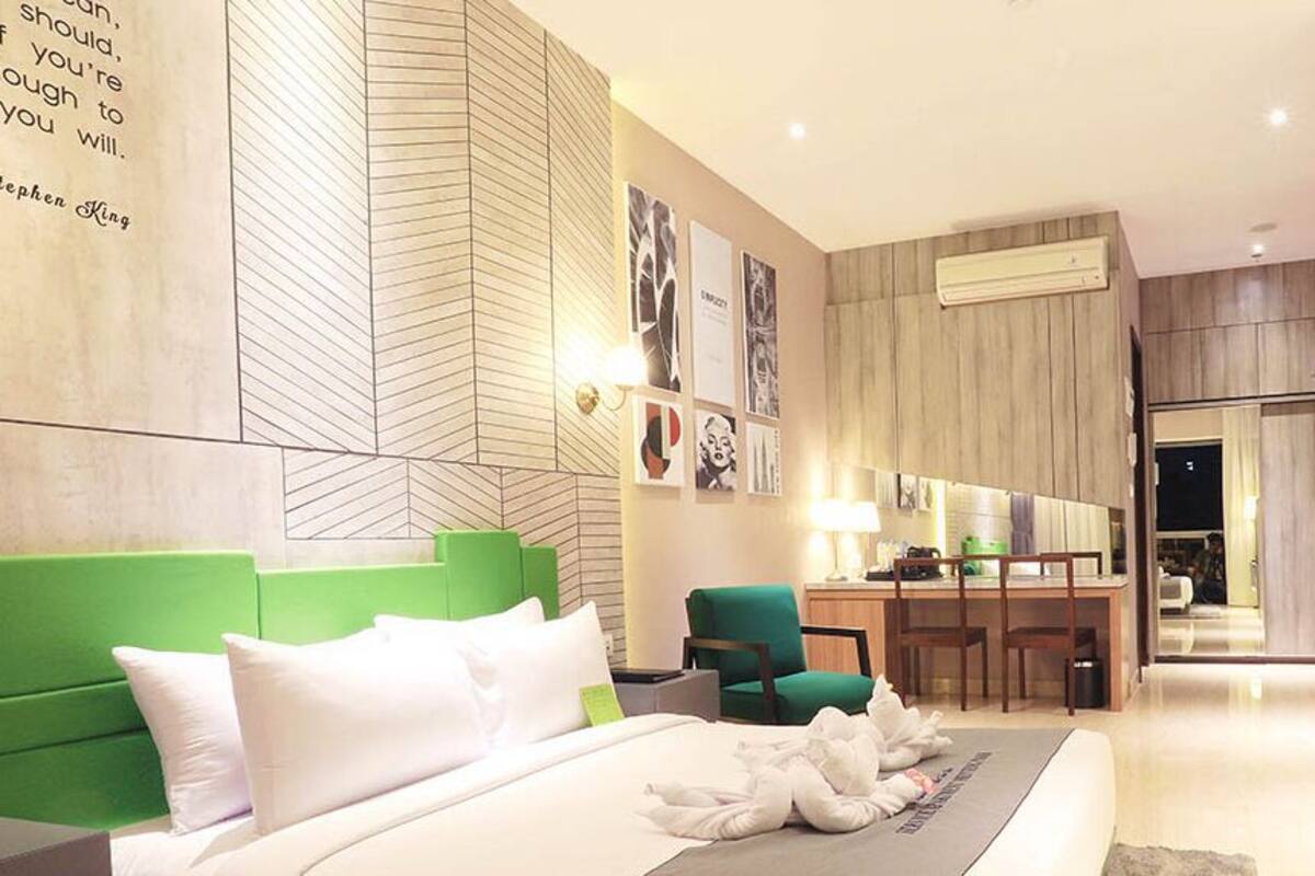 Ein modernes Hotelzimmer mit einem dunkelgrünen Kopfteil, einem Schreibtisch und einem Essbereich.