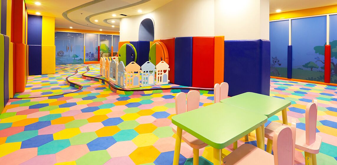 A children's play area with colorful hexagonal flooring, play structures, and seating.