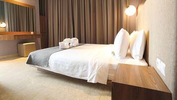 Une chambre d’hôtel moderne avec un grand lit, une table de chevet en bois et un luminaire fixé au mur.