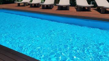 Una piscina al aire libre de temporada, tumbonas