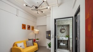 A modern living room with a yellow sofa, a floor lamp, and artwork on the wall. - Cooliv Waterfront (Singapore)