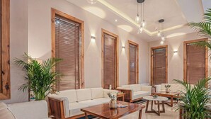 A spacious living area with a sofa, coffee tables, and potted plants. - The Bodhi Tree Ladakh (Leh)