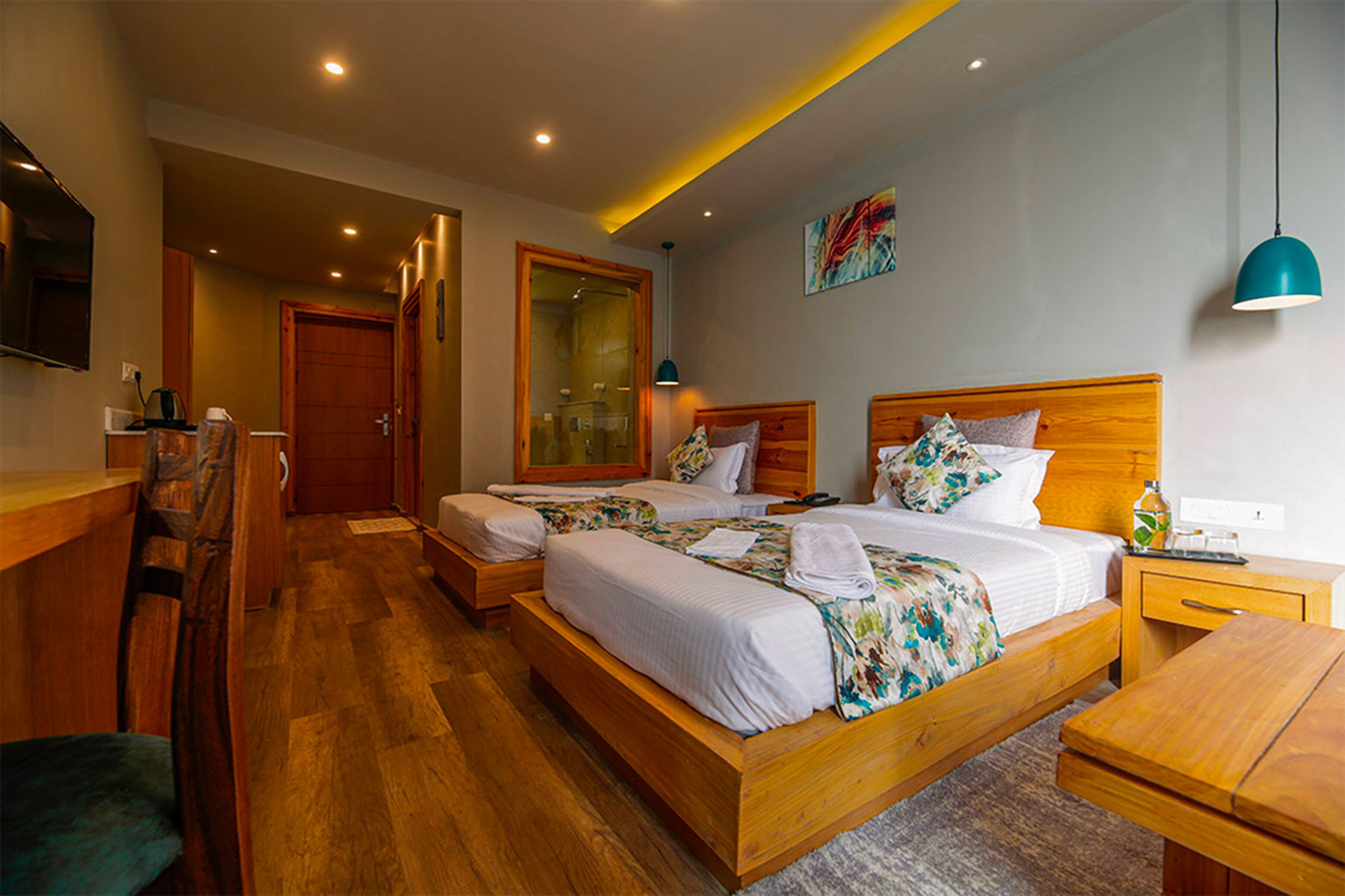 A hotel room with two wooden beds, a desk, a chair, and a TV.