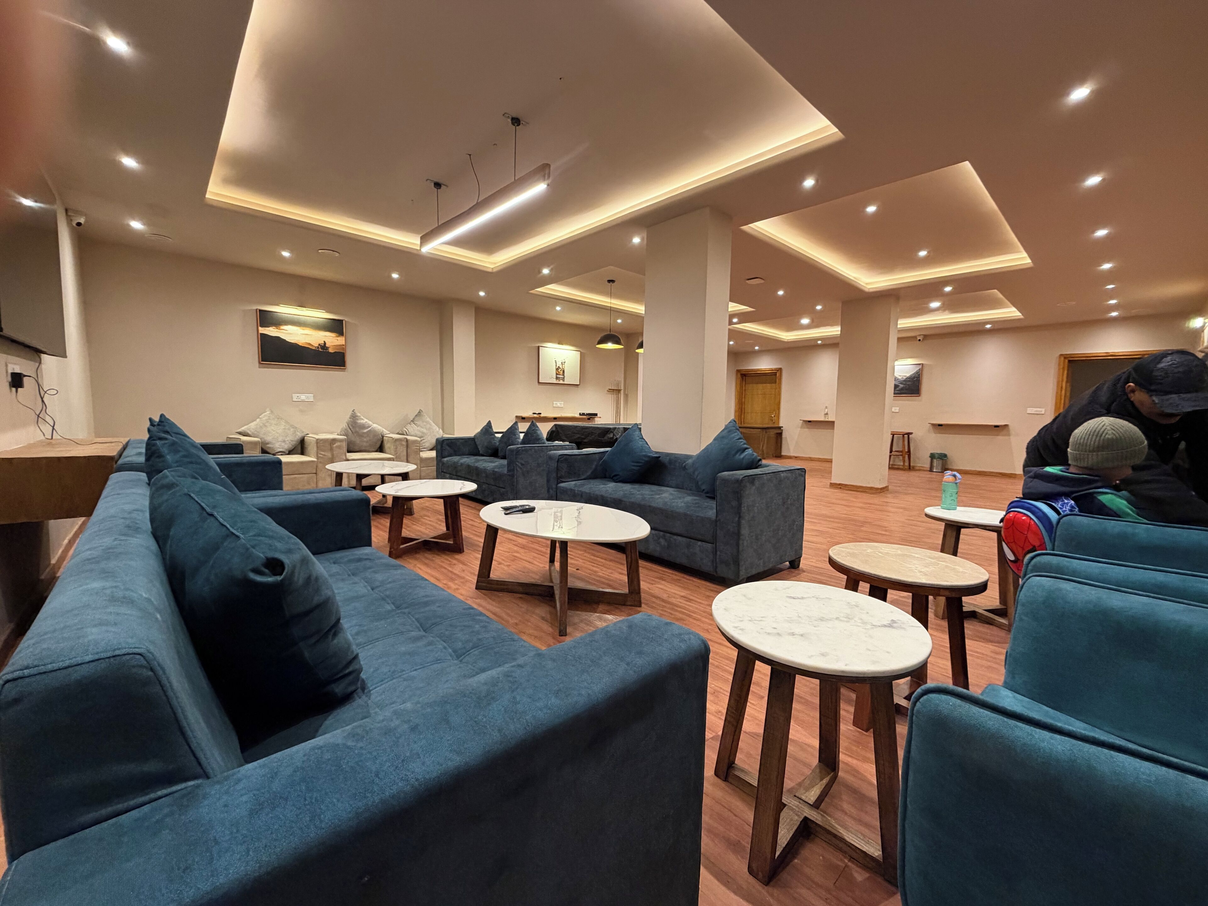 A modern lounge area with sofas, round tables, and a wooden floor.