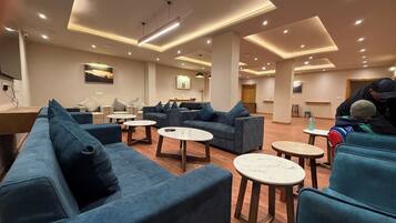 A modern lounge area with sofas, round tables, and a wooden floor.
