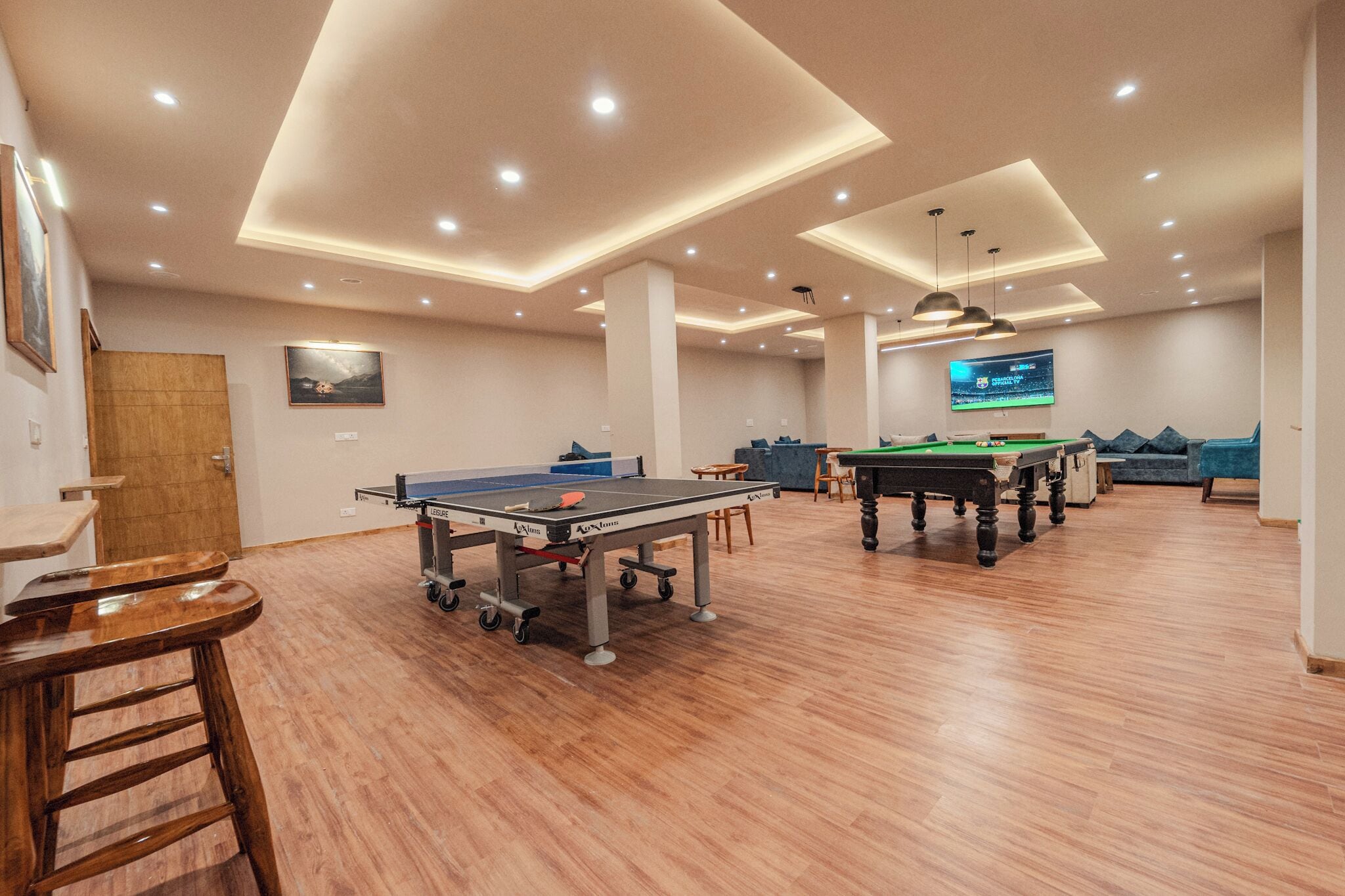 A spacious indoor area with a ping pong table, pool table, and seating area.