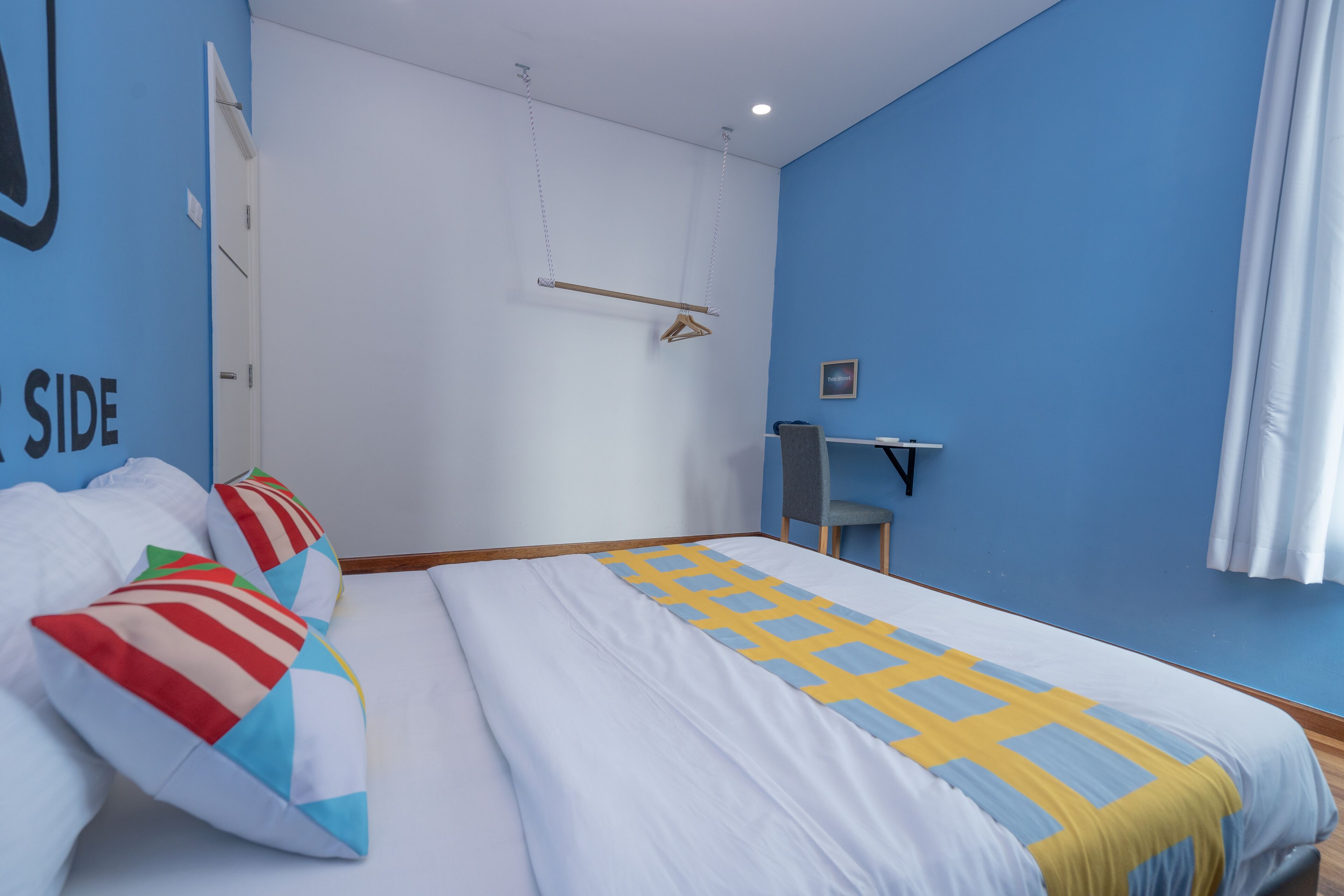 A bedroom with a bed, pillows, a desk, and a chair.